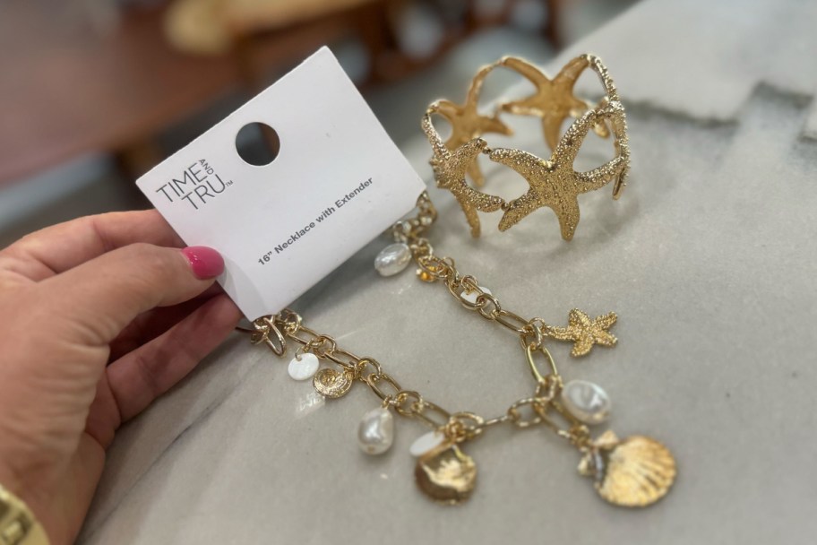 hand holding starfish necklace and bracelet in packaging