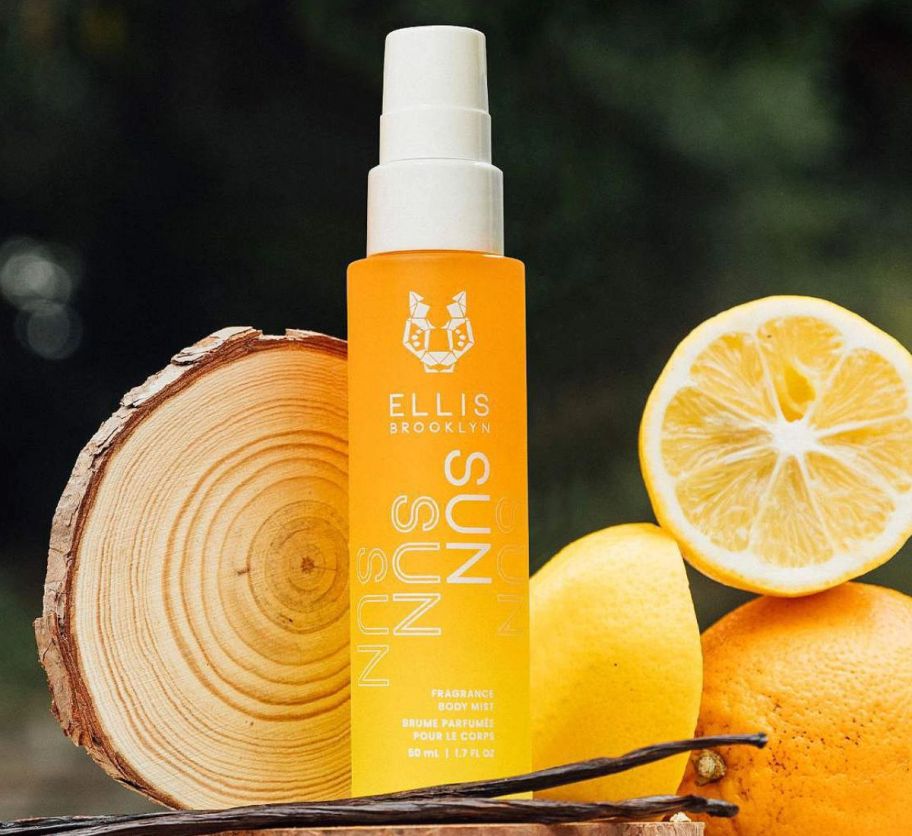 a bottle of body mist shown with lemon slices, vanilla beans and a wood slice. 