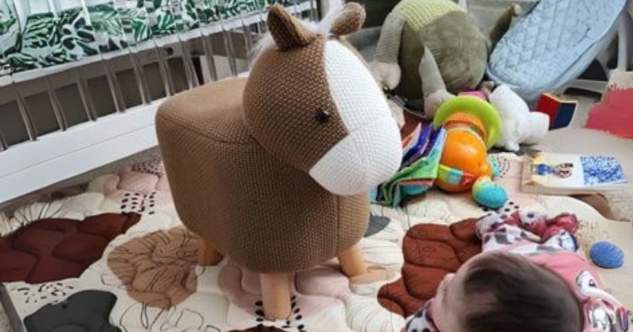 baby looking up at a brown cow foot still in bedroom