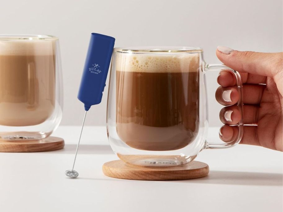blue mini milk frother leaning against coffee cup