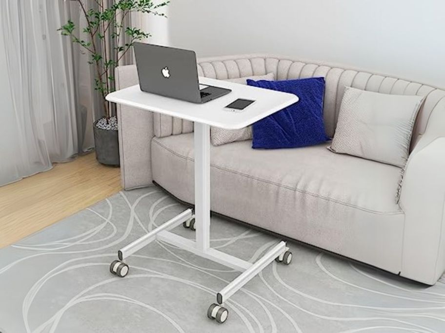 white Dumos Small Adjustable Standing Laptop Desk in front of couch