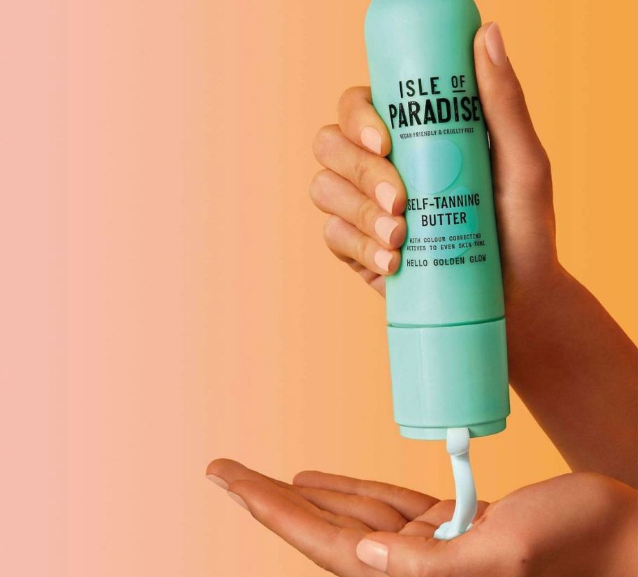 a womans hand holding a bottle of tanning butter