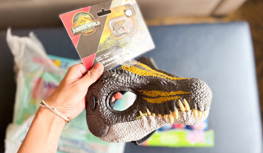 hand holding a dinosaur mask in their hand