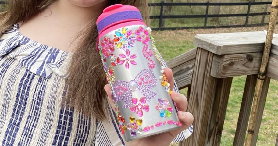 kid holding pink water bottle full of sticker gems