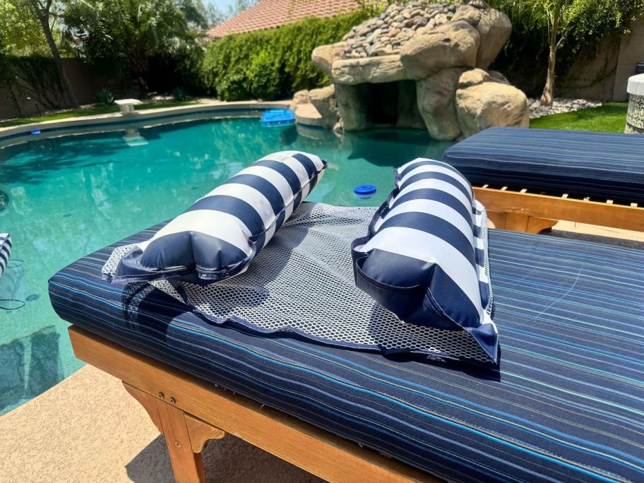 stripe navy and white pool float sitting on lounge chair by pool