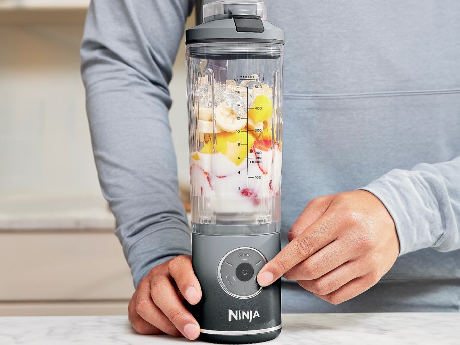 person using gray and black ninja blast blender 