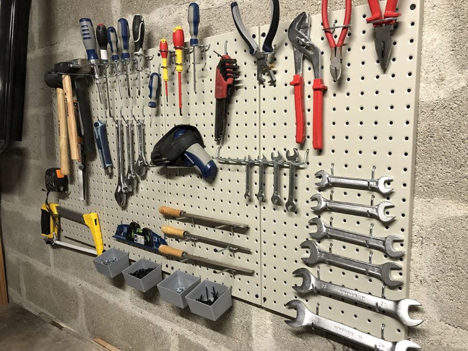 grey pegboard on wall with tools hanging on it