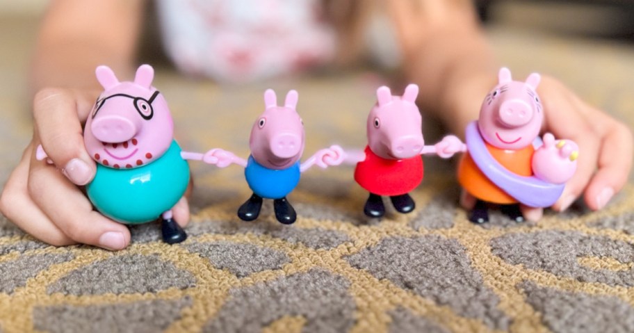 peppa pig family toys lined up on a rug