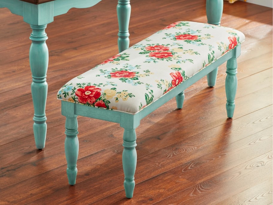 a floral fabric dining bench with teal legs in a kitchen