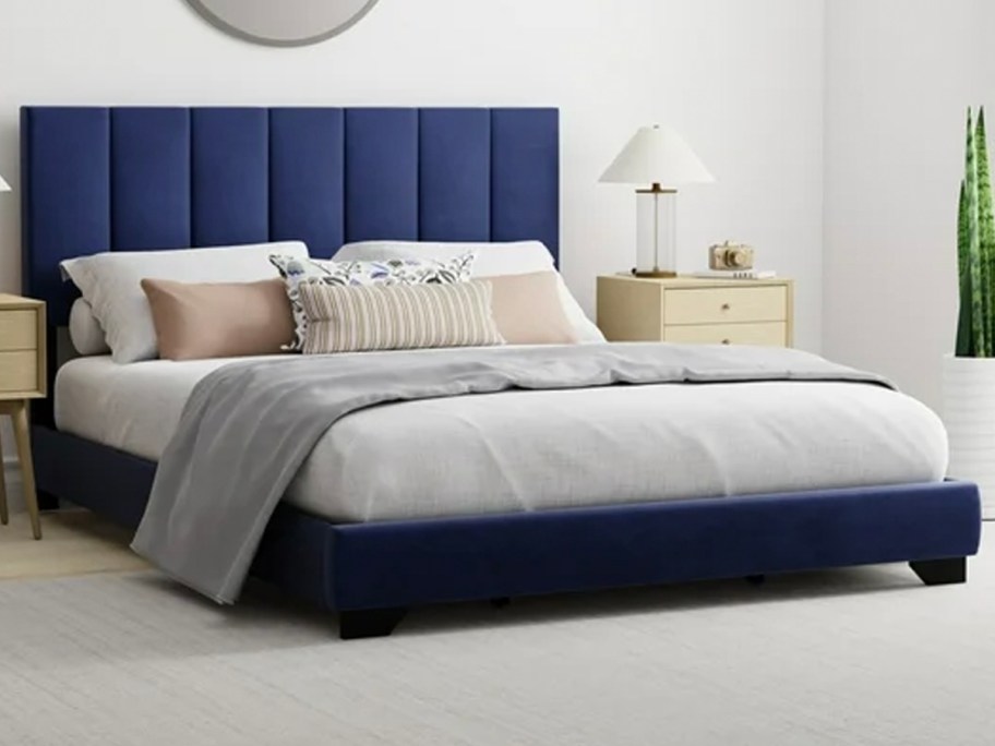 blue upholstered bed with white and gray blankets on top 