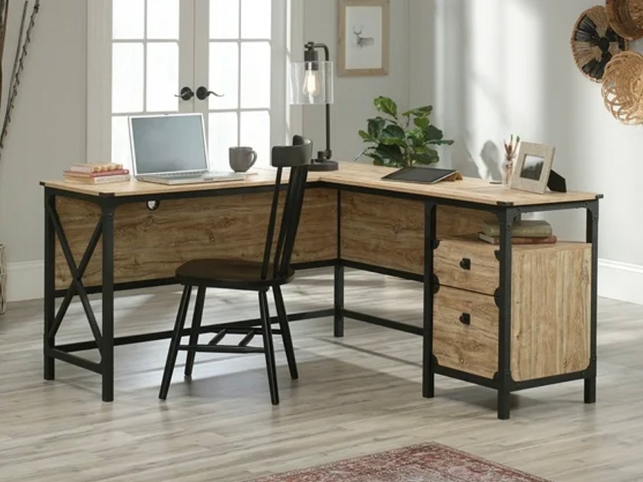 brown and black desk with laptop, lamp, and picture frames