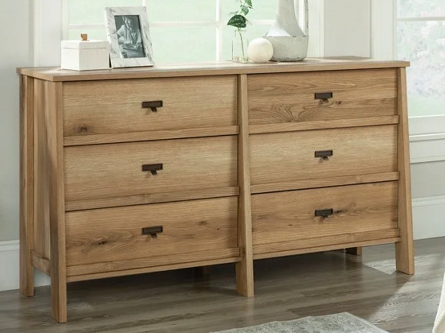 light brown 6 drawer dresser with picture frames and decor on top 