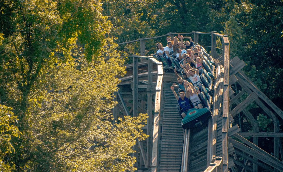 wooden roller coaster with people in coaster 