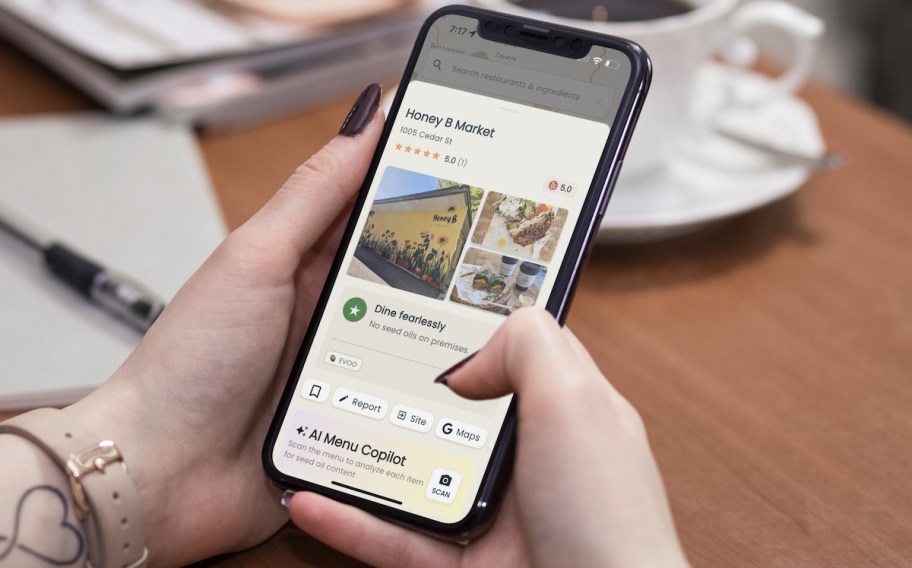 hand holding phone with seed oil free restaurant on screen