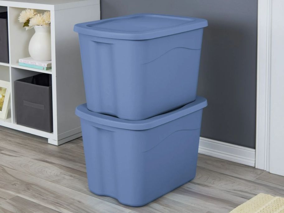 two blue plastic storage bins with lids stacked next to a white storage cubby