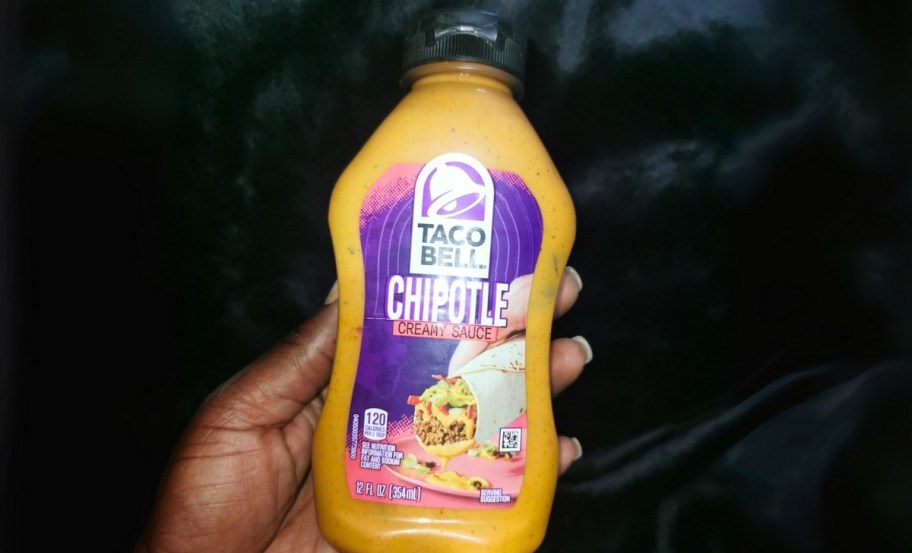 a hand holding a bottle of taco bell chipotle creamy sauce