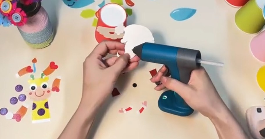 person using a glue gun to make a craft on a table