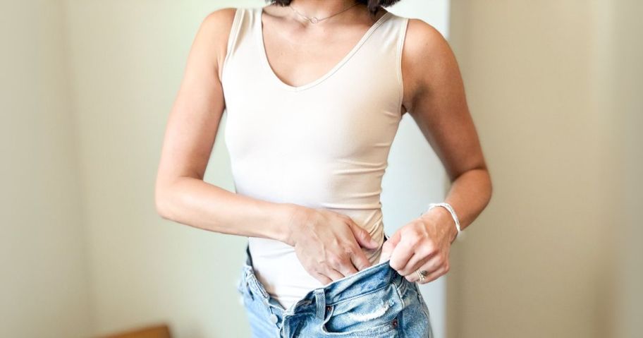 woman wearing beige vanity fair cami and tucking it into her jeans