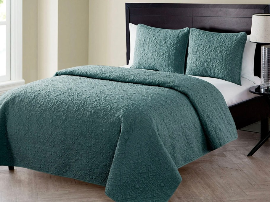 green comforter and pillows on bed 