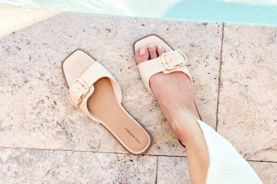 raffia buckle sandal on one foot near pool