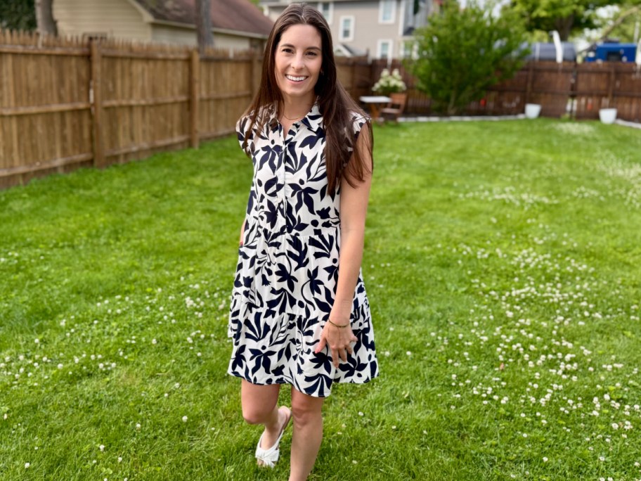 woman standing in grass in black and white floral dress