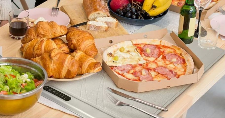grey food warming tray on table with pizza and other food on it
