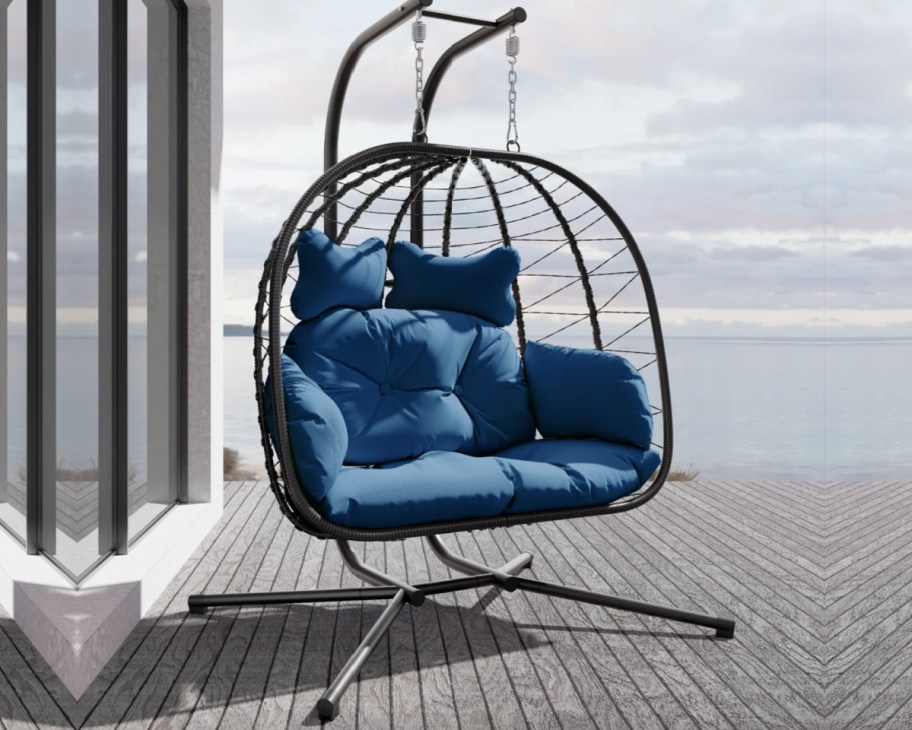 blue cushion two person egg chair on deck at beach