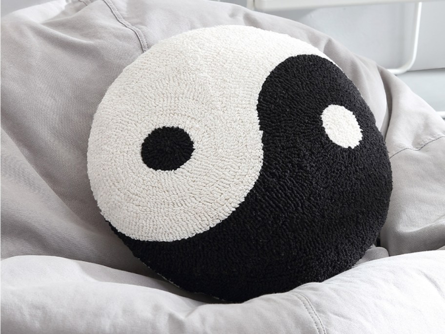 a yin yang pillow on a bed with other pillows