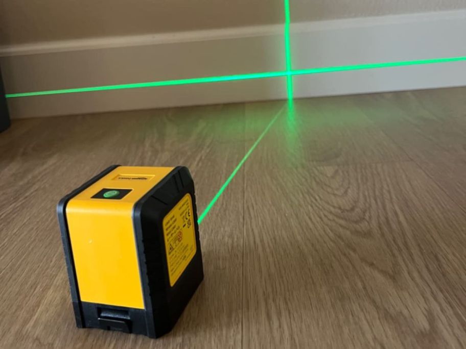 A yellow laser level projecting a green laser on the wall