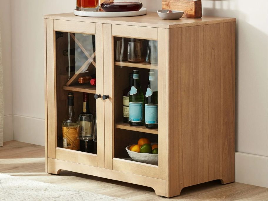 A Better Homes & Gardens Aster Bar Cabinet filled with wine and liquor