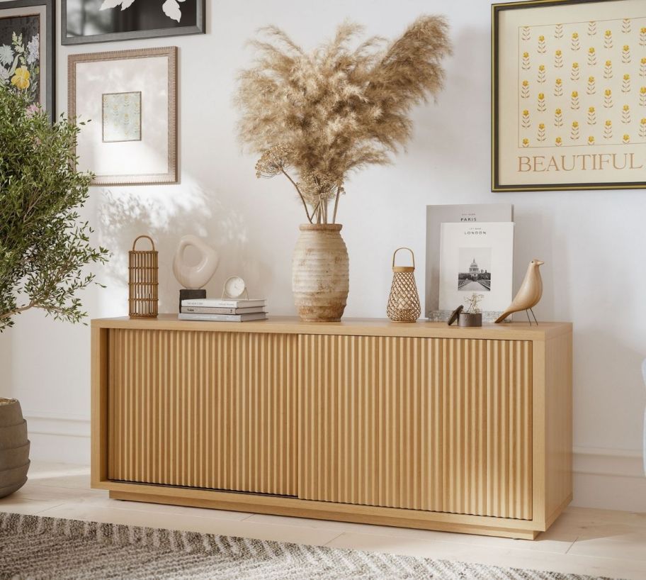 a fluted media console in honey colored wood