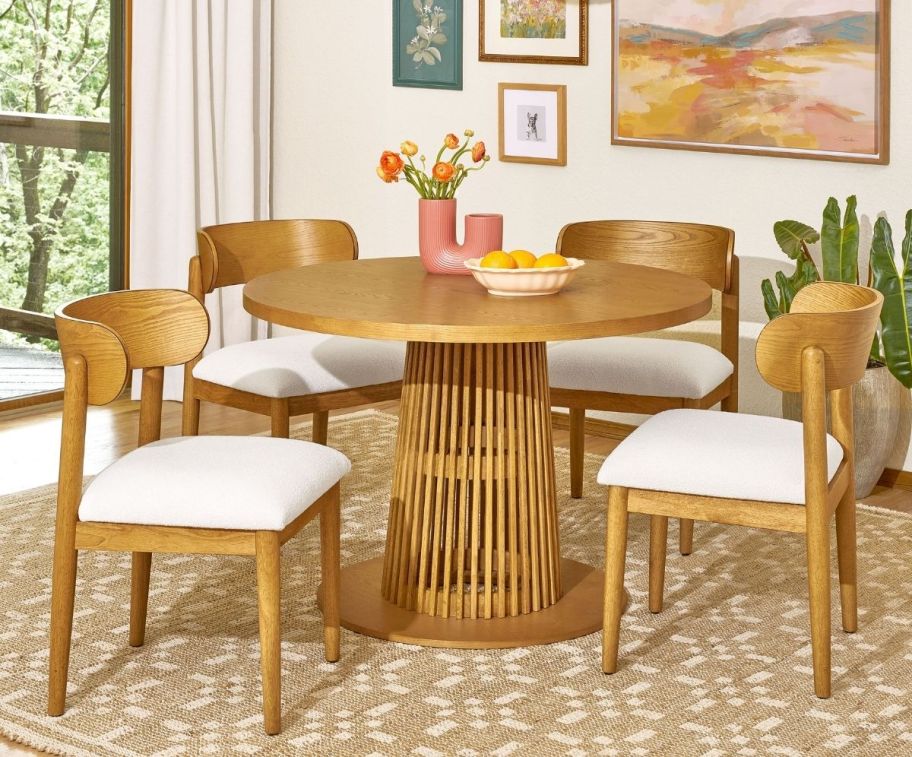 a round dining table in warm honey colored wood