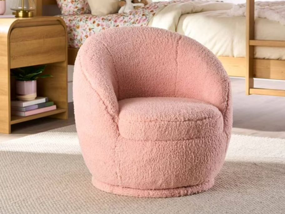 A child's swivel chair in pink sitting in the middle of a bedroom