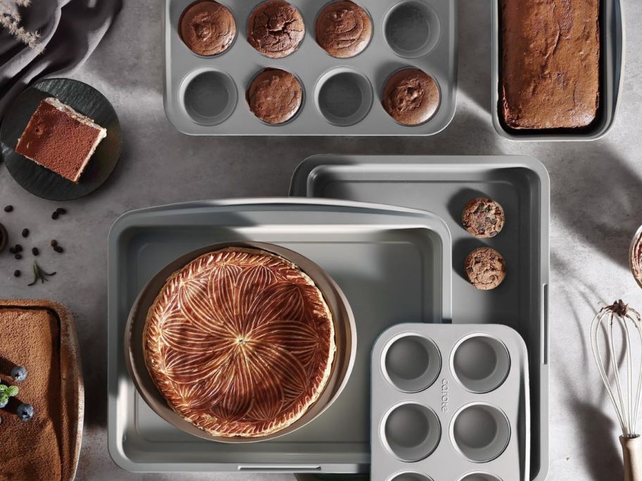 9 metal baking pans with cakes and muffins in them