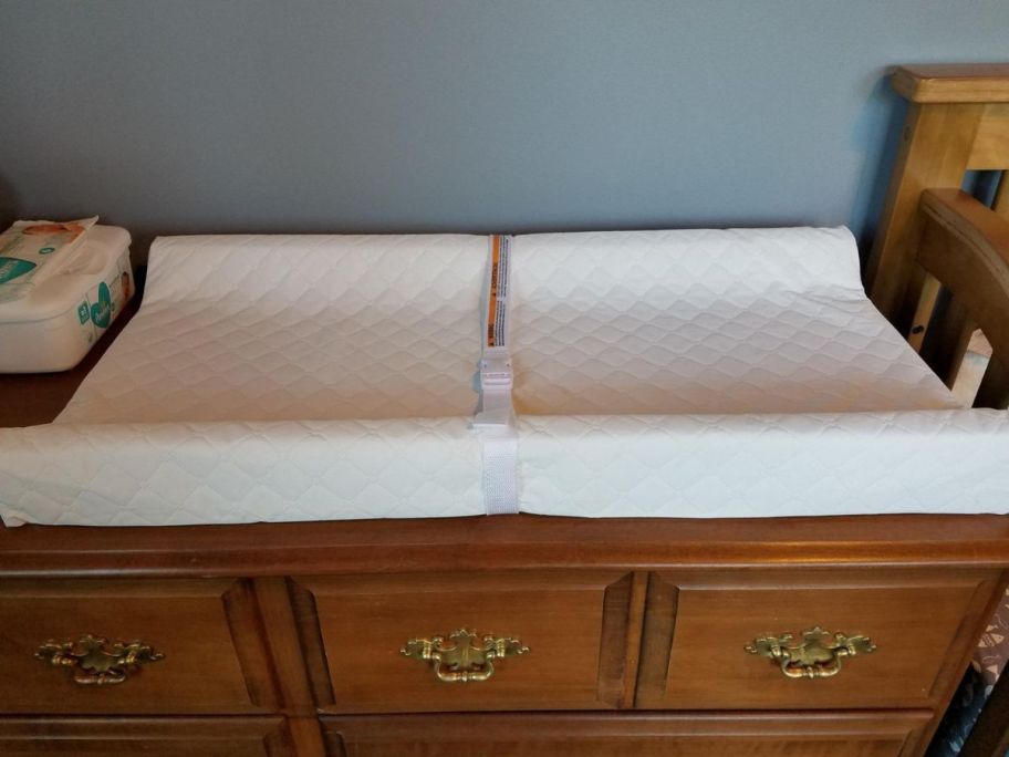 A dresser with a Summer Infant Changing Pad w/ Waterproof Liner & Safety Strap on it