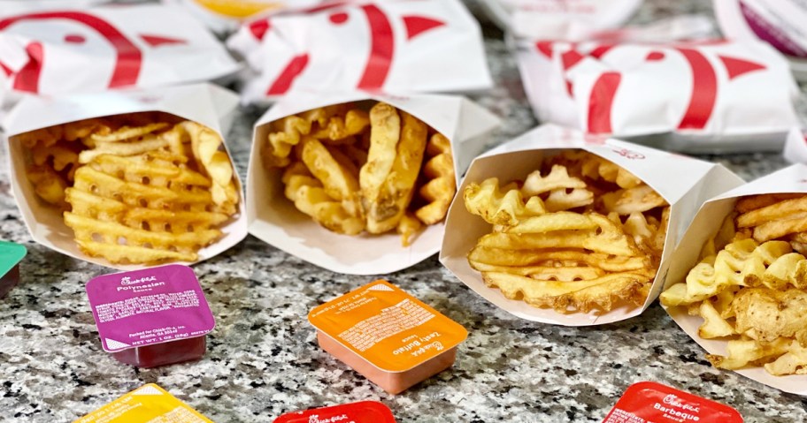 4 sleeves of Chick-fil-A fries on counter with different sauces