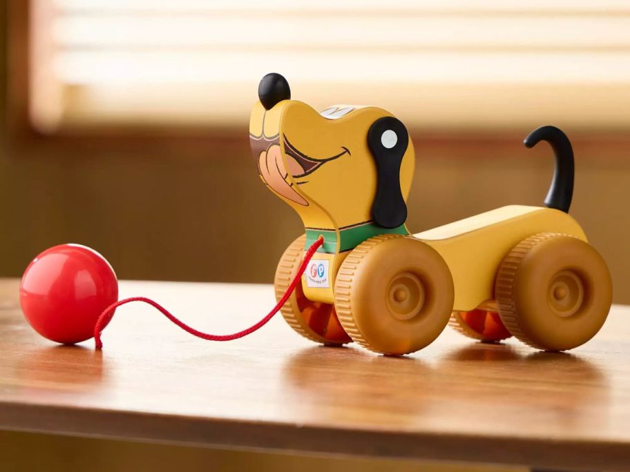 A wooden toy dog with a ball