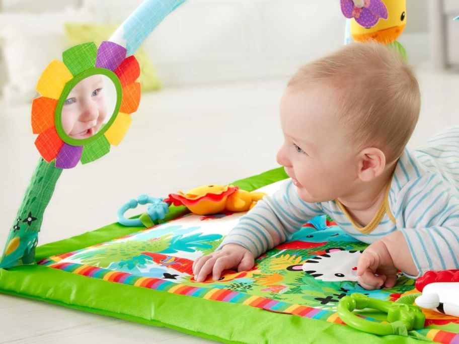 A baby doing tummy time on a Fisher-Price Baby Playmat Rainforest Deluxe Gym