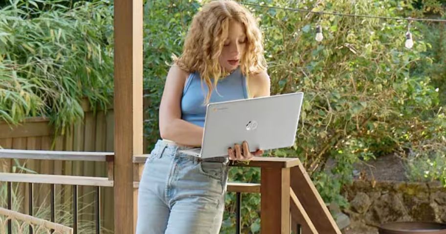 Teenage girl standing on a deck using an HP laptop