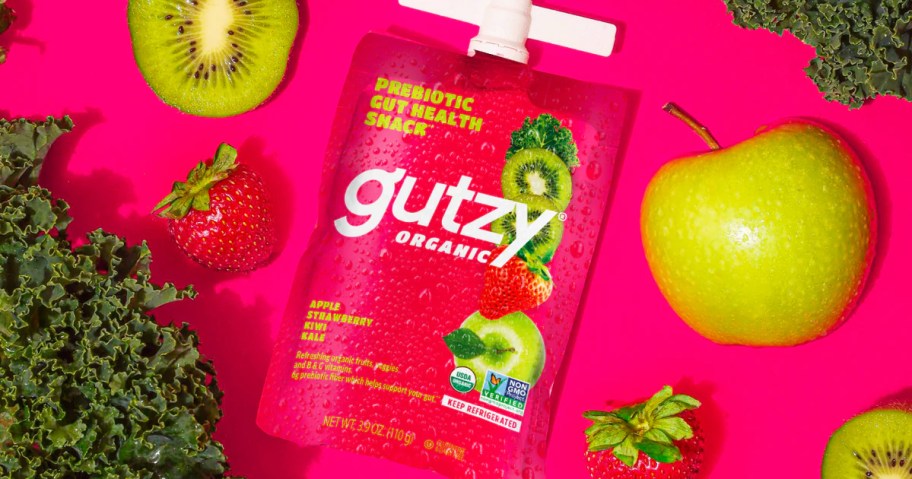 Gutzy fruit & veggie pouch surrounded by kiwi, strawberry, apple, and kale