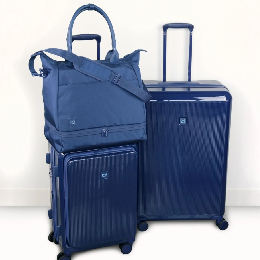 a set of blue hardside luggage with a matching carry on tote bag