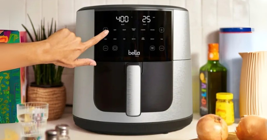 hand pushing a button on a large air fryer