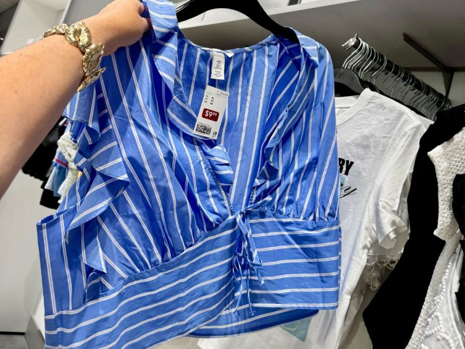 Hand holding an H&M clearance tank top on a hanger