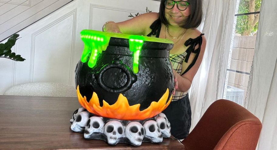 woman mixing candy inside of her halloween light up caldron