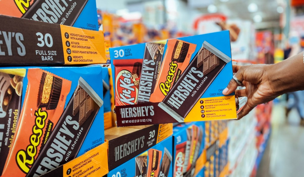 Person grabbing warehouse a size box of Hershey's candy bars from store shelf