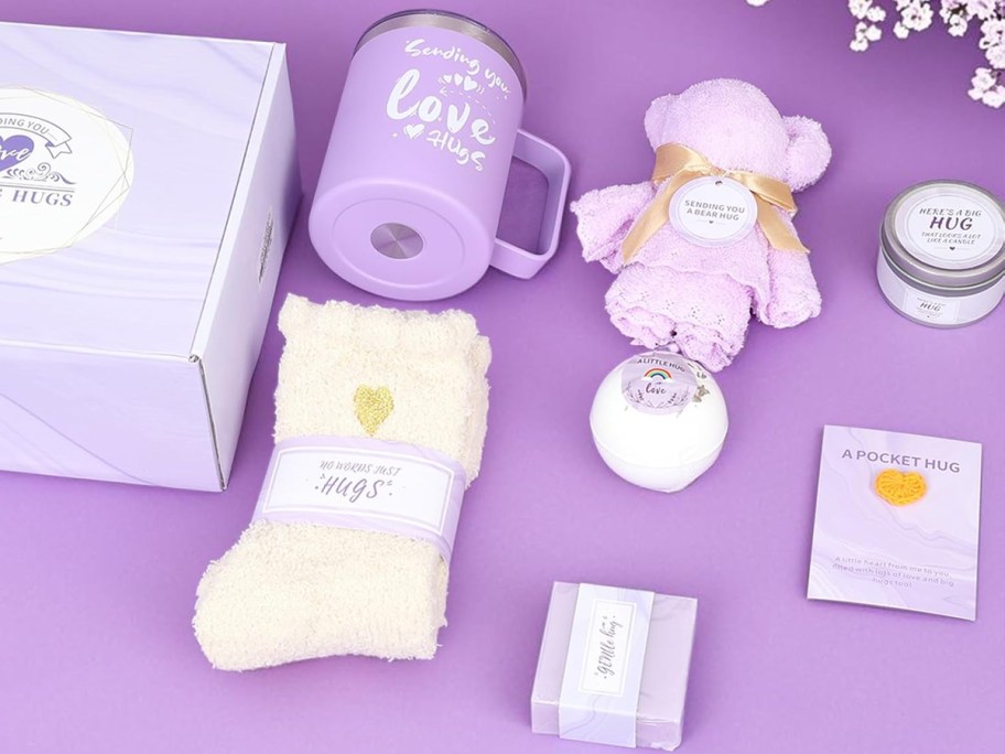 purple mug, socks, bear towel, bath bomb, candle, and soap bar near a gift box
