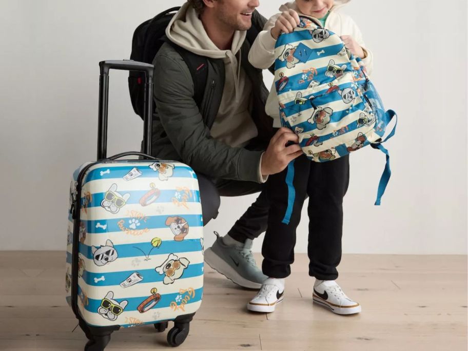A man and a little boy with a matching suitcase and backpack with dogs wearing sunglasses on it