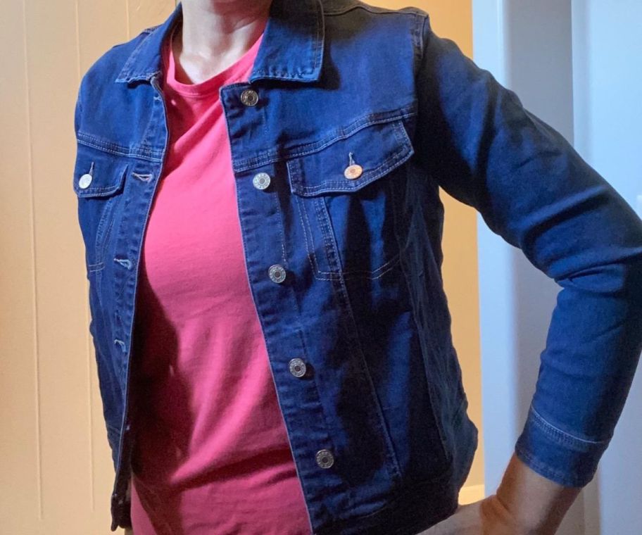 A woman wearing a dark blue denim jacket and a pink shirt