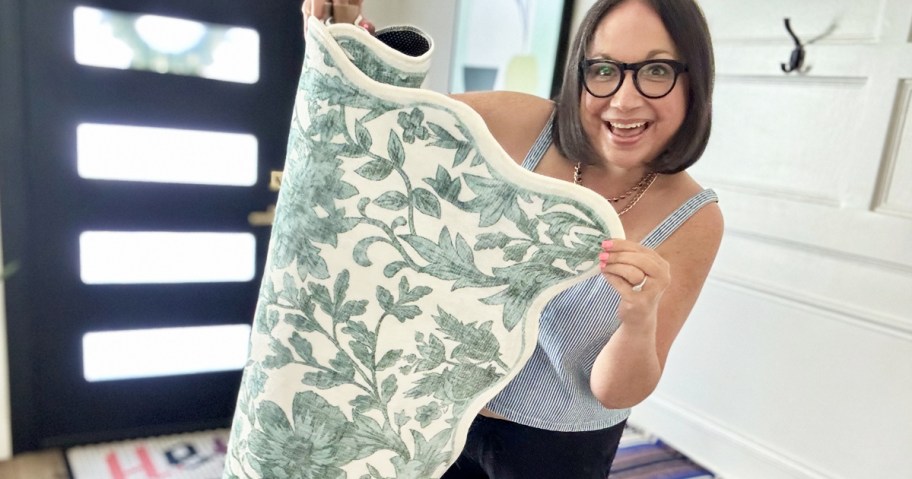 woman holding up a blue and white scalloped edge area rug