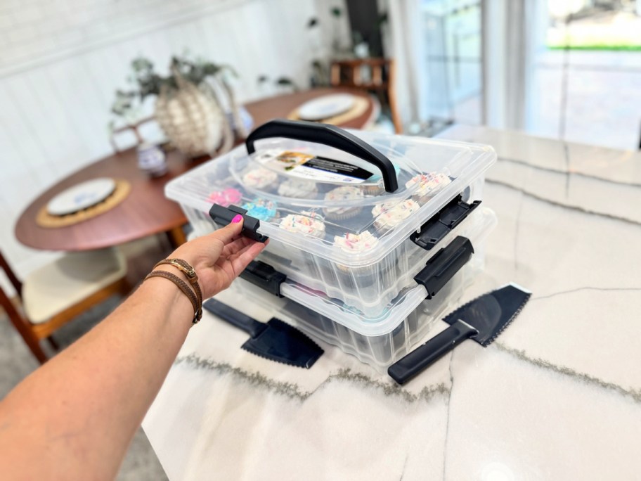 woman reaching for the handle of a Mainstays cupcake carrier on a kitchen counter